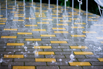 Rainy weather in  city. Splashes of rain on pavement tiles. It rains_