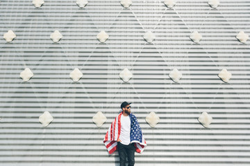 Happy hipster man holding American or USA flag. He is wearing casual clothes.