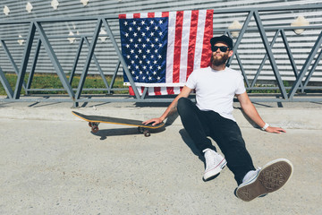 Happy hipster man holding American or USA flag. He is wearing casual clothes.