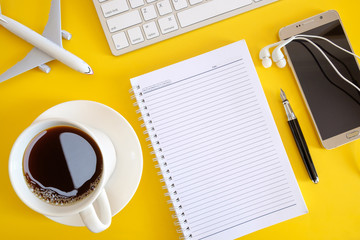 Flay lay of empty note book, computer keyboard, smartphone and coffee.