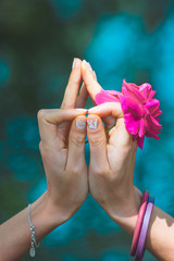 woman hands with flower in yoga mudra gesture outdoor in nature in front lake