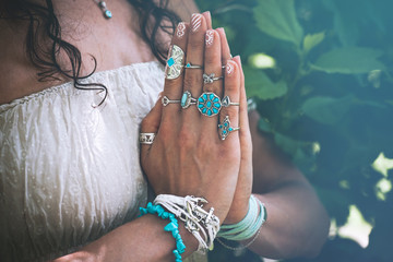 close up of yoga woman hands in namaste gesture with lot of boho style jewelry rings and bracelets...
