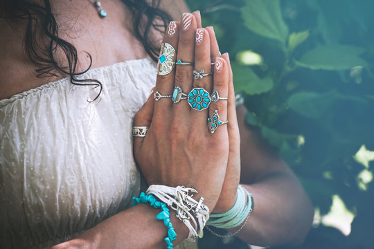 close up of yoga woman hands in namaste gesture with lot of boho style jewelry rings and bracelets outdoor