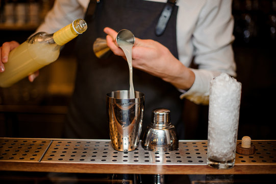 Bartender adding an alcoholic drink into a steel shaker
