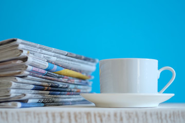 Newspapers folded and stacked with blue background, selective focus.