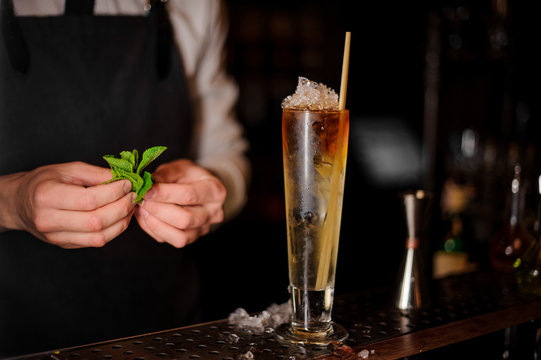 Barman holding a mint leaves near the summer cocktail
