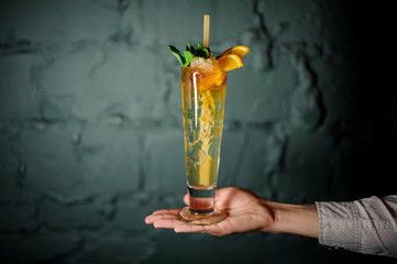 Professional bartender holding on the hand a summer orange cocktail