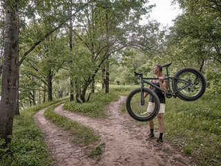 A trained man is riding a fat bike along forest paths.