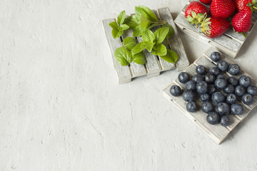 Fresh berries strawberries blueberries mint on a wooden stand, grey background with Copy space for text