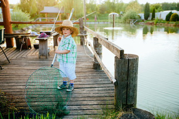 Cute little boy in hat holding big fishing net at the ready. Summer vacation concept.