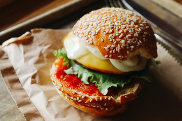 Burger with meat. Homemade cheese burger or hamburger on a wood plate served to put on wood table with copy space. Fast food for breakfast or lunch.