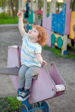 The boy plays in the playground, shows a finger at the sky.