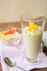 fresh smoothies in glass glass with banana, orange, mango, on wooden background.