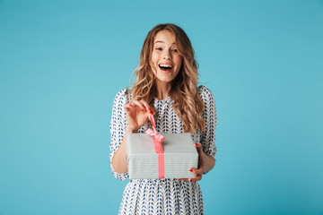 Surprised happy blonde woman in dress holding gift box