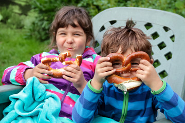 Zwei lustige Geschwister im Garten mit Brezeln