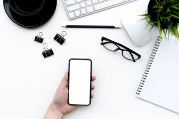 Flat lay of top view Business woman use smartphone on modern white desk work table with computer laptop and stationary in home office includes copyspace for add text or graphic