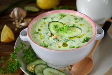 Cold soup Tarator with kefir, cucumbers and pine nuts in a ceramic tureen. Bulgarian cuisine meal