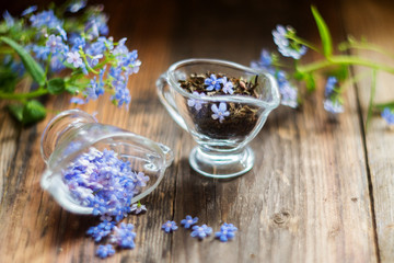 Obraz na płótnie Canvas flower tea and a bouquet of forget-me-nots on a wooden background