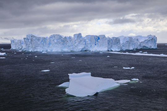Large blue tabular iceberg, small iceberg and coast of Errera Channel, Danco Coast, Antarctic Peninsula, Antarctica