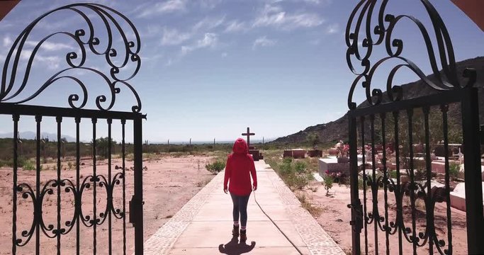 Woman opens the iron door of a cemetery, walks inside the graveyard. 4k