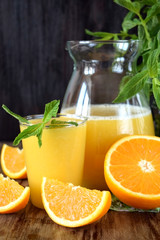 Orange juice in a glass and jug on a wooden table