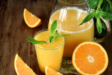 Orange juice in a glass and jug on a wooden table