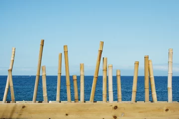 Wandaufkleber Seascape with the blue sky and the ocean in the background and in the foreground a decoration with bamboo canes in the island of Tenerife © vali_111