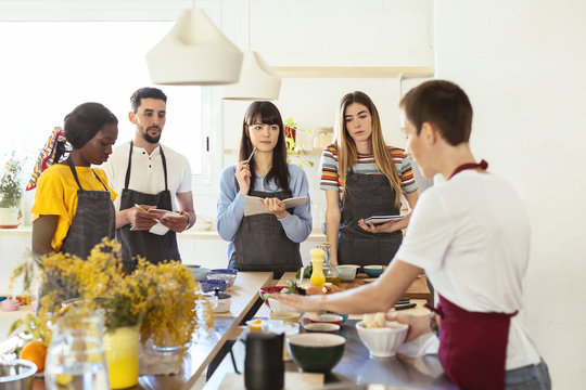 Friends in a cooking workshop listening to instructor