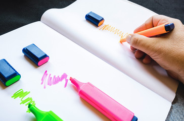 hand holds and uses markers, highlighters on paper sheet