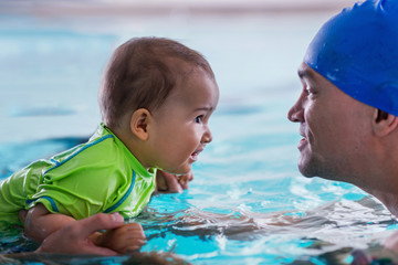 Father with baby boy in the swimming pool on swimming class