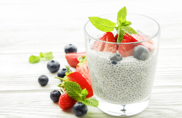Healthy nutritious vegan superfood dessert with organic berries and chia seeds with different serving options on wooden table.