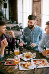 Fototapeta na wymiar Men In Pub Drinking Beer And Eating Food