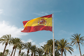 Flag of Spain beautiful and big to the background palms and blue sky with some clouds. Prepped...