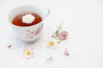 Obraz na płótnie Canvas Cup of tea with daisies on white background