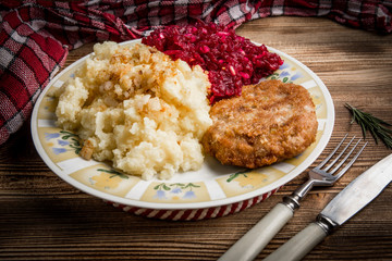 Pork cutlet with minced meat served with boiled potatoes and beetroot.