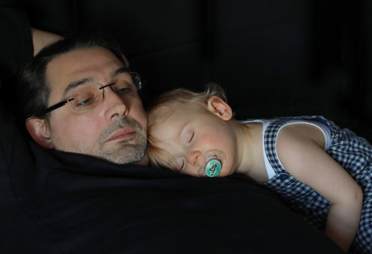 Petit gar&ccedil;on b&eacute;b&eacute; avec la tetine dans le bouche dort paisiblement allong&eacute; sur son papa. Moment complicit&eacute;