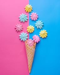 Ice cream cone with pink,blue, yellow meringues on a  colorful  background. Sweet summer concept. Top view. Flat lay.Pastel colors.Dessert