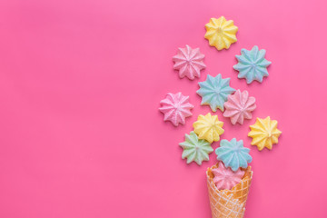 Ice cream cone with pink,blue, yellow meringues on a  colorful  background. Sweet summer concept. Top view. Flat lay.Pastel colors.Dessert