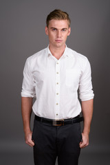 Fototapeta premium Young handsome businessman with blond hair against gray backgrou