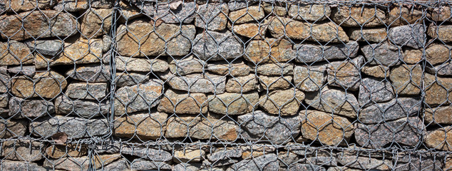 Stone wall in a metal grid as a background