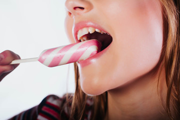 Laughing girl holding big lollipop.Beautiful woman with creative makeup holding a candy, closeup portrait