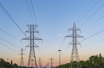 Electrical poles and power lines in a  suburbian area at sunset