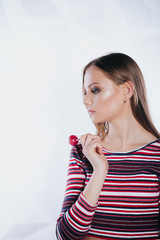 Sexy woman with red lips holding lollipop, beauty closeup. Beautiful woman with creative makeup holding a candy, closeup portrait