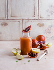 Delicious detox smoothie on rustic wooden board with blood oranges and apples