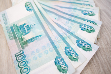 business, finance, saving, banking concept - close up bundle of money Russian Banknotes thousand rubles on wooden table