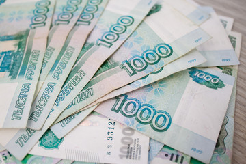 business, finance, saving, banking concept - close up bundle of money Russian Banknotes thousand rubles on wooden table