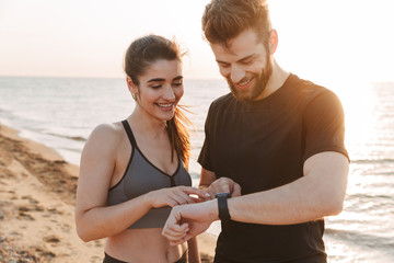 Joyful young sport couple looking at smartwatch