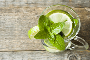 Fresh citrus lemonade in a glass of lime on a wooden background. Copy space for text