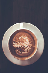 top view of Coffee cup with latte art on wooden table . Selective focus white cup.color vintage style.