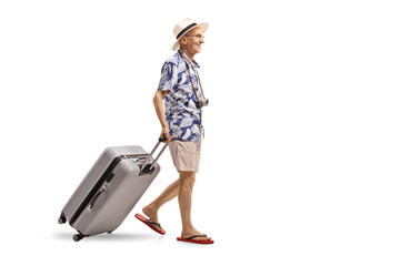 Elderly tourist walking and dragging a suitcase